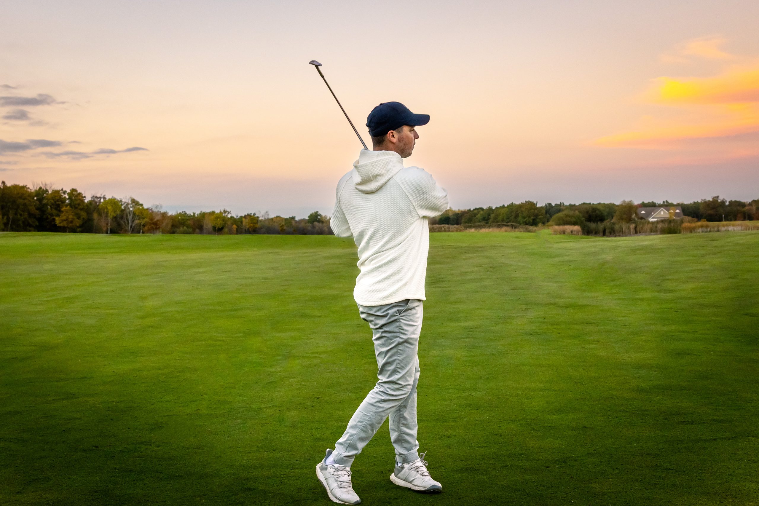 Golfer putting on the green surrounded by hickory trees and a beautiful landscape in the early morning light