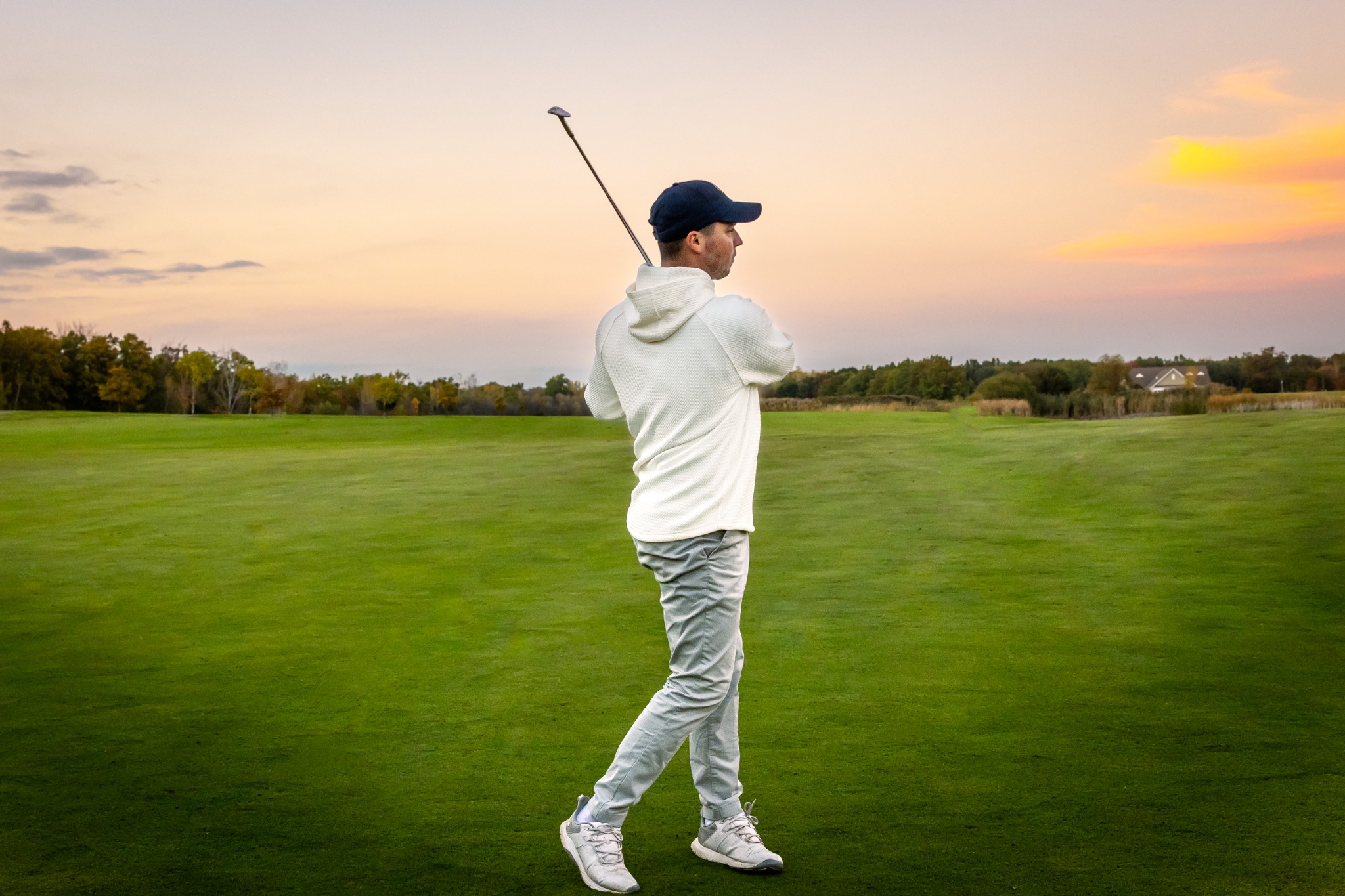 Golfer putting on the green surrounded by hickory trees and a beautiful landscape in the early morning light